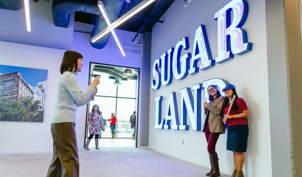 Two ladies posing in front of the Sugar Land sign